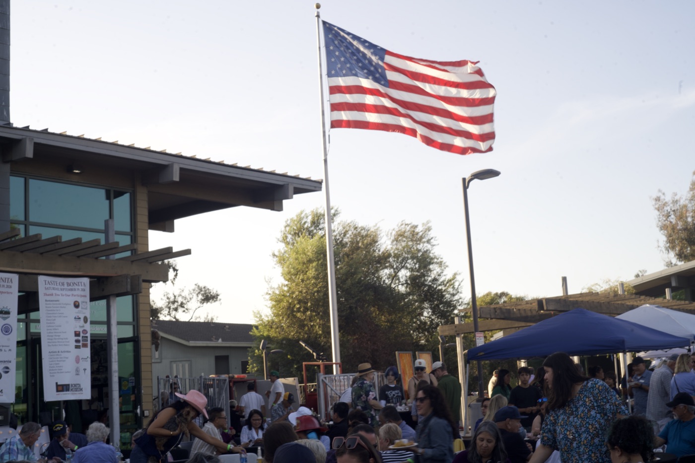 Festival-goers seated at tables beneath a large American flag, with the Taste of Bonita banner visible.
