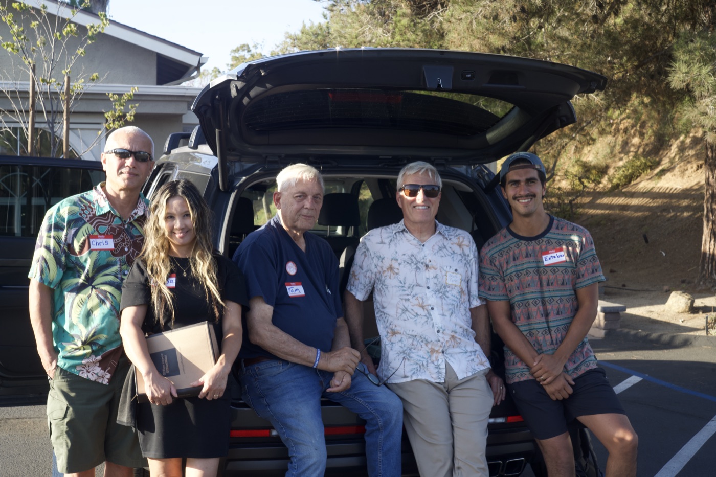 Five members of the outreach team, name tags on, standing by the car loaded with supplies before the event.